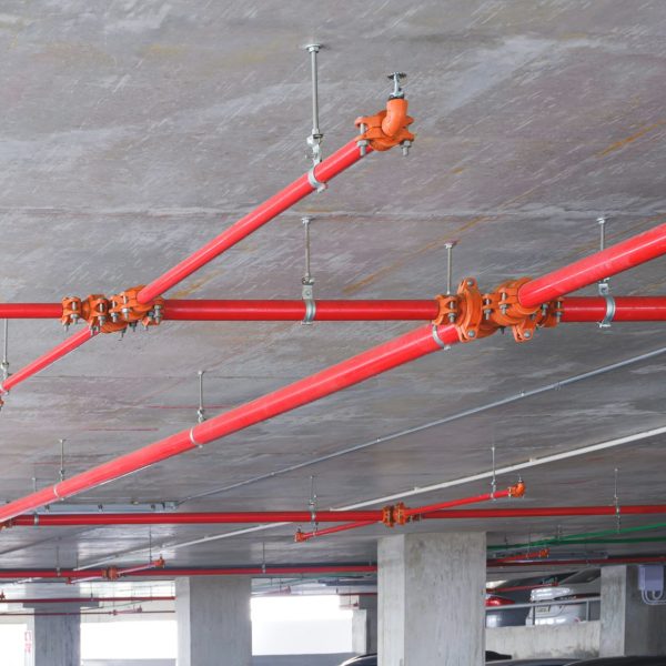 Red fire protection water pipeline system on ceiling inside of parking garage building